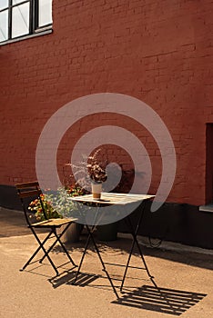 Summer porch against a brick wall. Wooden table and chairs. Summer atmosphere