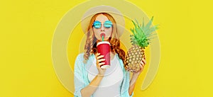 Summer portrait of attractive woman drinking juice holding pineapple wearing a straw hat, sunglasses