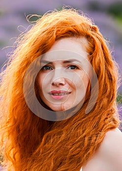 Summer portrait of a beautiful girl with long curly red hair