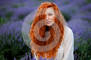 Summer portrait of a beautiful girl with long curly red hair