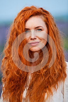 Summer portrait of a beautiful girl with long curly red hair