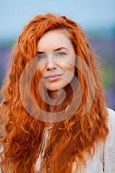 Summer portrait of a beautiful girl with long curly red hair