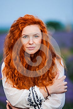 Summer portrait of a beautiful girl with long curly red hair