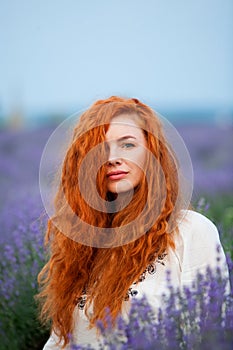 Summer portrait of a beautiful girl with long curly red hair