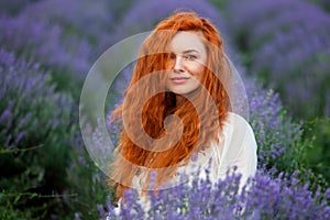 Summer portrait of a beautiful girl with long curly red hair