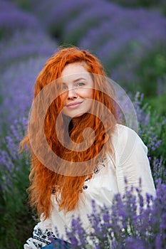 Summer portrait of a beautiful girl with long curly red hair