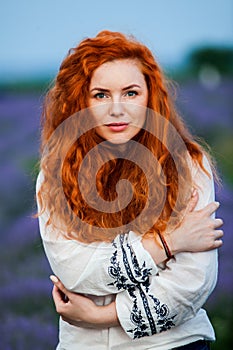 Summer portrait of a beautiful girl with long curly red hair