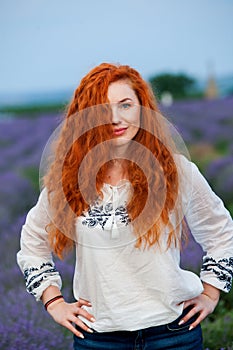 Summer portrait of a beautiful girl with long curly red hair