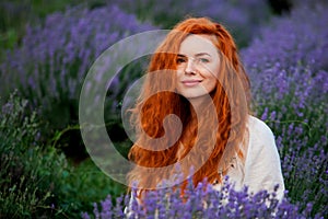 Summer portrait of a beautiful girl with long curly red hair