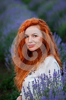 Summer portrait of a beautiful girl with long curly red hair