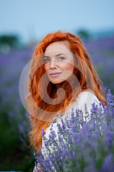 Summer portrait of a beautiful girl with long curly red hair