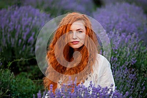 Summer portrait of a beautiful girl with long curly red hair