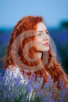 Summer portrait of a beautiful girl with long curly red hair