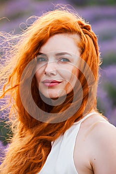 Summer portrait of a beautiful girl with long curly red hair