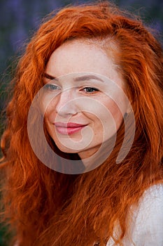 Summer portrait of a beautiful girl with long curly red hair