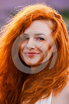 Summer portrait of a beautiful girl with long curly red hair