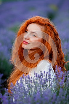 Summer portrait of a beautiful girl with long curly red hair