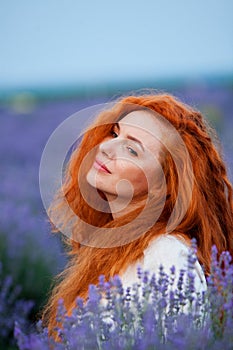 Summer portrait of a beautiful girl with long curly red hair