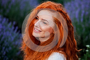 Summer portrait of a beautiful girl with long curly red hair