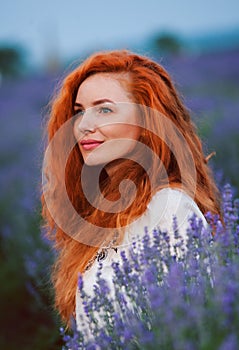 Summer portrait of a beautiful girl with long curly red hair