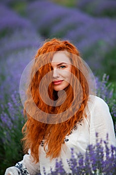 Summer portrait of a beautiful girl with long curly red hair