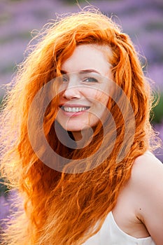 Summer portrait of a beautiful girl with long curly red hair