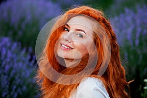 Summer portrait of a beautiful girl with long curly red hair