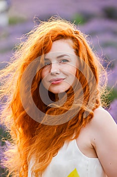 Summer portrait of a beautiful girl with long curly red hair