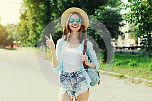 Summer portrait beautiful smiling young woman wearing a straw hat and backpack in the city park