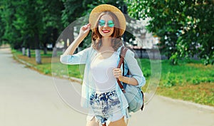 Summer portrait beautiful smiling young woman wearing a straw hat and backpack in the city park