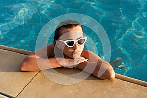 Summer portrait of a beautiful young girl with sunglasses in the swimming pool