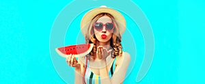 Summer portrait of beautiful young woman blowing her lips with red lipstick sending air kiss with slice of watermelon wearing