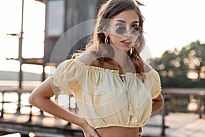 Summer portrait of a beautiful young woman in an elegant summer dress with fashion sunglasses walks outdoors