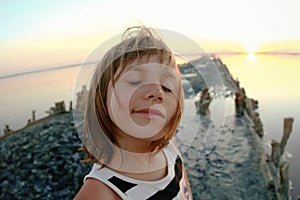 Summer portrait of a girl close-up, on a salt lake in the sunset, girl with contented and playful faces