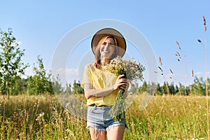 Summer portrait of happy 30s woman with bouquet of wildflowers