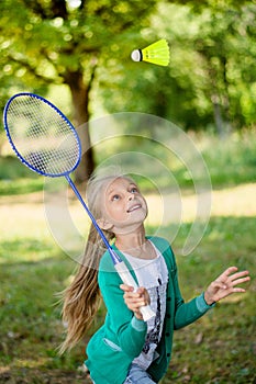 Summer portrait of a happy girl on picnic plays badminton
