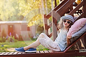 Summer portrait of happy kid girl relaxing on lounger