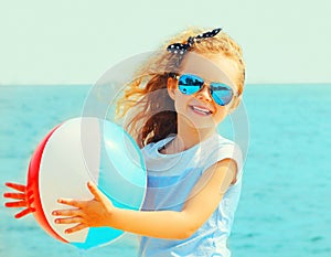 Summer portrait of happy smiling little girl child playing with inflatable water ball on beach over sea