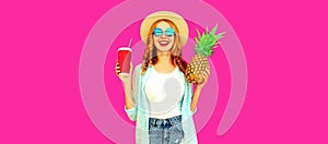 Summer portrait of happy smiling woman with cup of juice and pineapple wearing straw hat, sunglasses on pink background