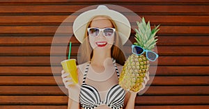 Summer portrait happy smiling woman with pineapple and cup of juice wearing a summer straw hat on a background