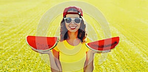 Summer portrait of happy smiling young woman eating fresh juicy slice of watermelon on the grass in the summer park