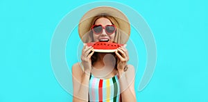 Summer portrait happy smiling young woman eating a slice of watermelon wearing straw hat on blue background