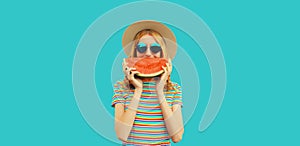Summer portrait of happy smiling young woman with fresh juicy slice of watermelon wearing straw hat on blue background