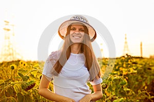 Summer portrait of happy young woman in hat with long hair in sunflower field