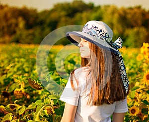 Summer portrait of happy young woman in hat with long hair in sunflower field