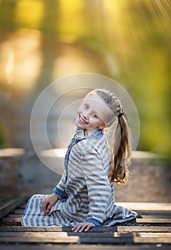 Summer portrait of little smile beautiful girl posing in the park
