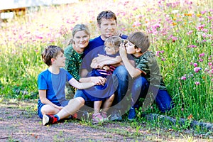 Summer portrait of parents with three children. Mother, father, two kids brothers boys and little cute toddler sister