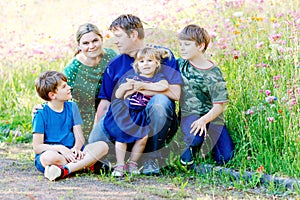 Summer portrait of parents with three children. Mother, father, two kids brothers boys and little cute toddler sister