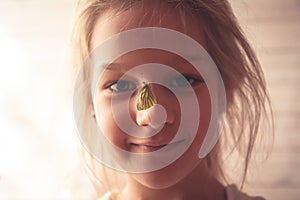 Summer portrait with smiling girl and butterfly on her nose symbolizing love to nature and kindness