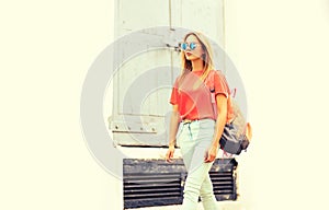 Summer portrait of stylish blonde young woman wearing backpack, sunglasses in the city